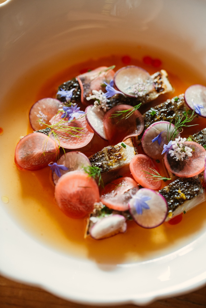 Plato del portfolio de Michael con producto del mar, vegetales y un caldo de color intenso