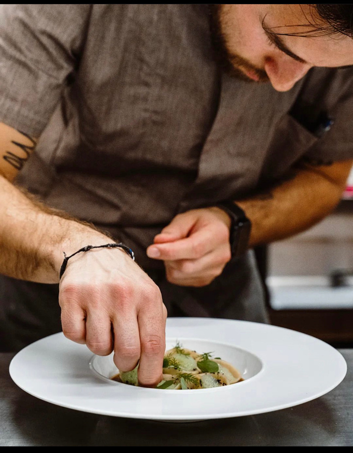 Michael trabajando con precisión en el emplatado de una creación gastronómica