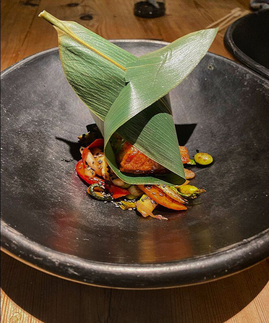 Creación de Giada con una delicada decoración verde y presentación sobre plato oscuro